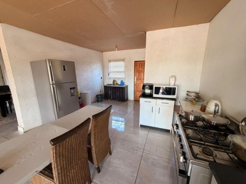 A functional kitchen area featuring tiled flooring, built-in cabinetry, and a gas stove, currently requiring cosmetic updates to the ceiling and wall finishes.