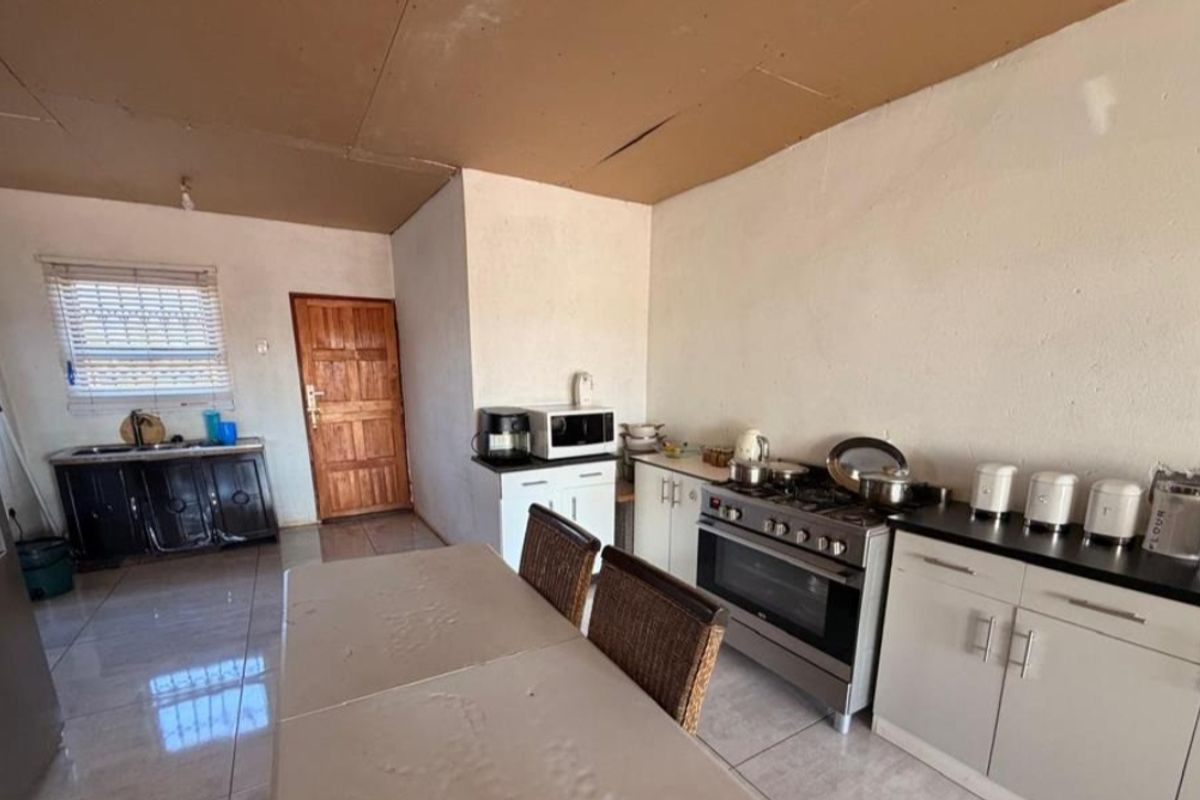 A functional kitchen area featuring built-in cabinetry, a gas stove, and tiled flooring, requiring ceiling repairs to improve the overall condition.