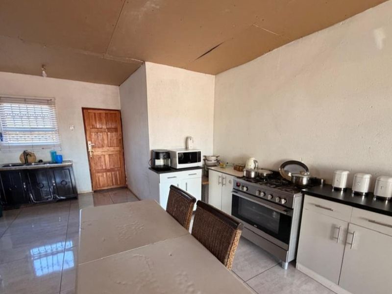 A functional kitchen area featuring built-in cabinetry, a gas stove, and tiled flooring, requiring ceiling repairs to improve the overall condition.