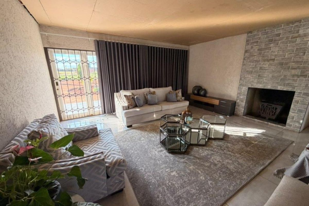 Spacious living room featuring a brick fireplace, tiled flooring, and direct access to the exterior through a sliding glass door with security gate.