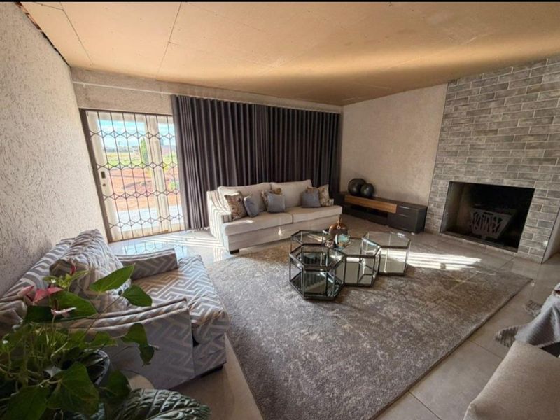 Spacious living room featuring a brick fireplace, tiled flooring, and direct access to the exterior through a sliding glass door with security gate.