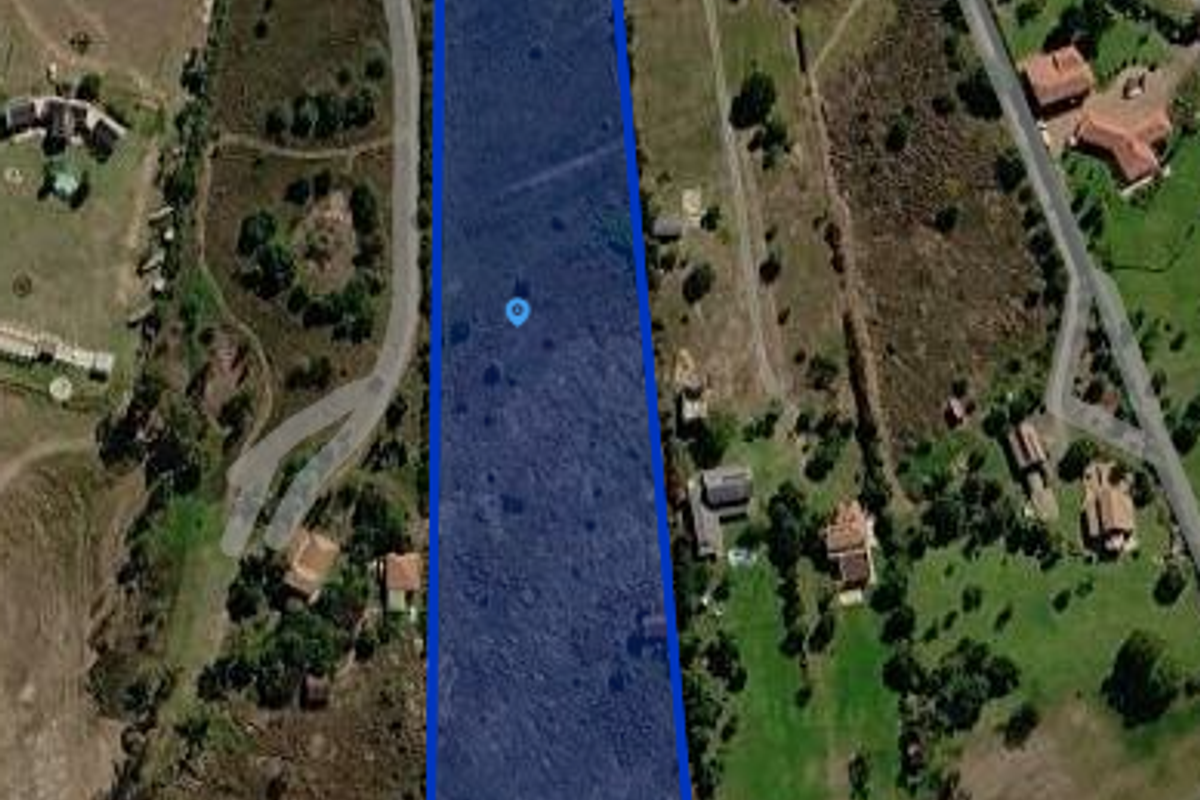 Aerial view of a vacant residential plot with road access, highlighting the property boundaries and surrounding landscape.