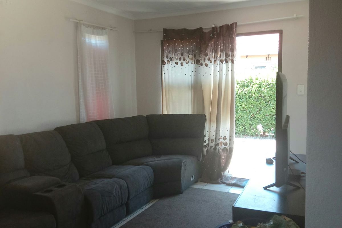 A living room featuring tiled flooring and a sliding glass door providing access to the outdoor area.