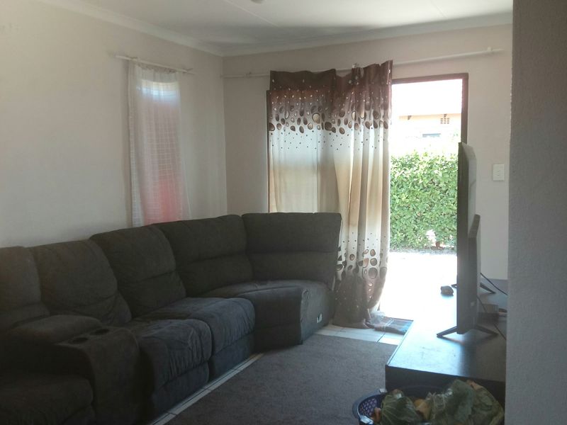 A living room featuring tiled flooring and a sliding glass door providing access to the outdoor area.