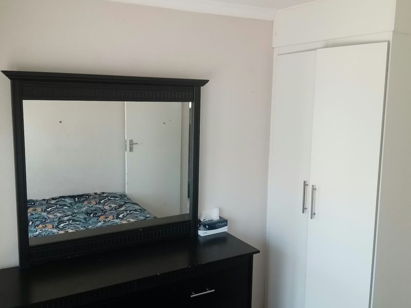 A bedroom featuring a white built-in wardrobe and tiled flooring, providing functional storage space.