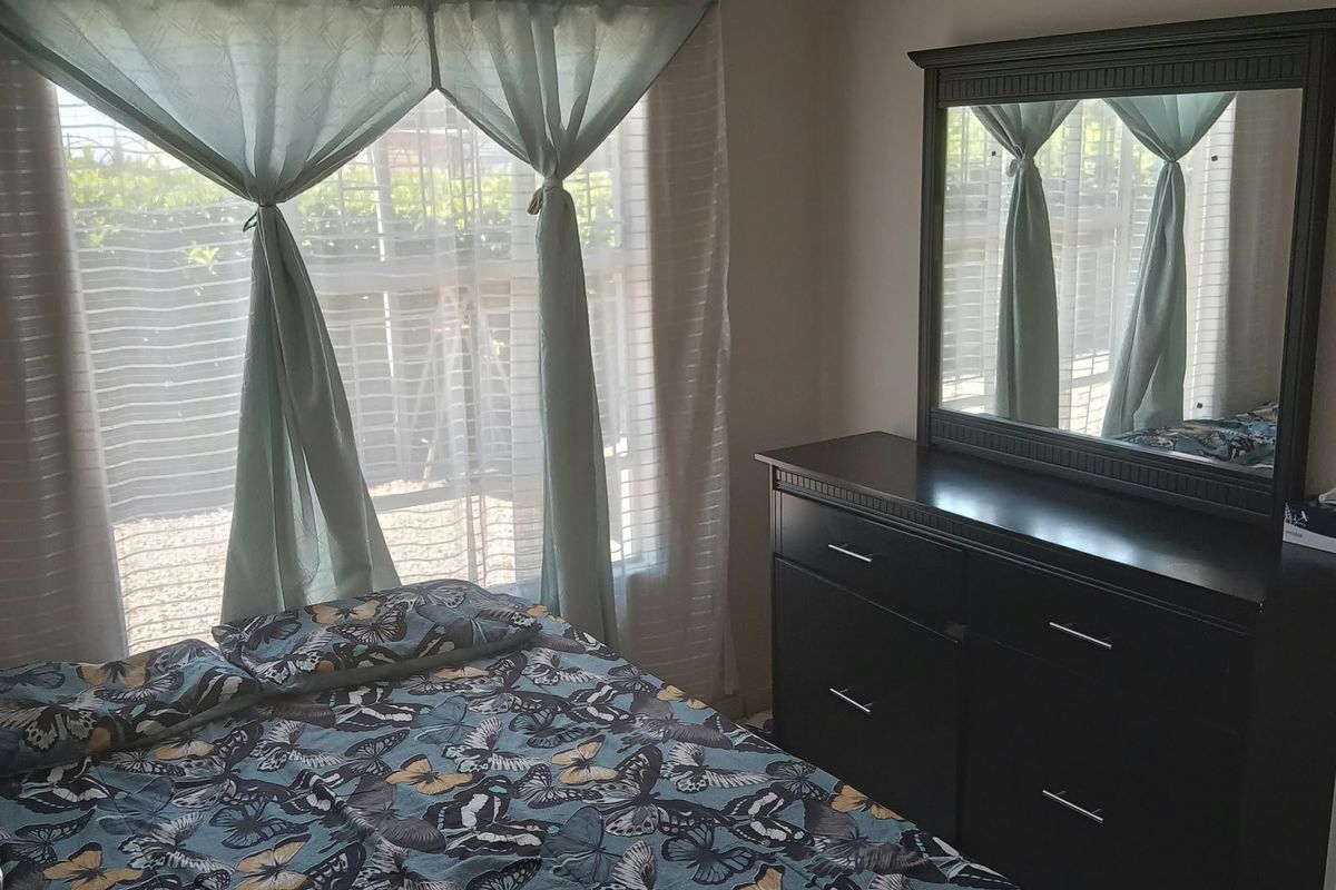 A bedroom featuring tiled flooring and natural light from a large window.