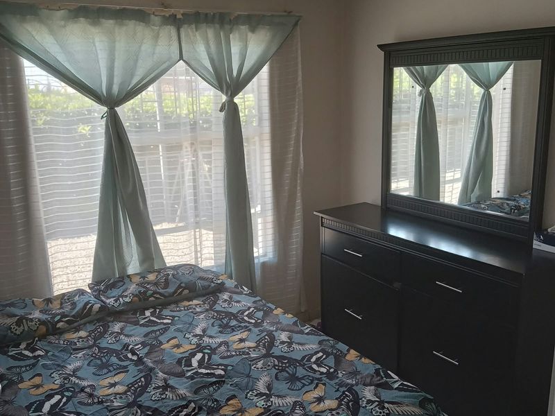 A bedroom featuring tiled flooring and natural light from a large window.