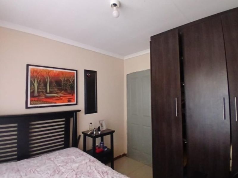 A bedroom featuring a dark wood built-in wardrobe and neutral wall finishes, providing a functional space with potential for cosmetic updates.