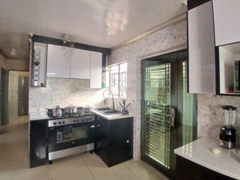Modern kitchen featuring high-contrast black and white cabinetry, stone countertops, a gas stove with oven, and a secure glass-panelled door.