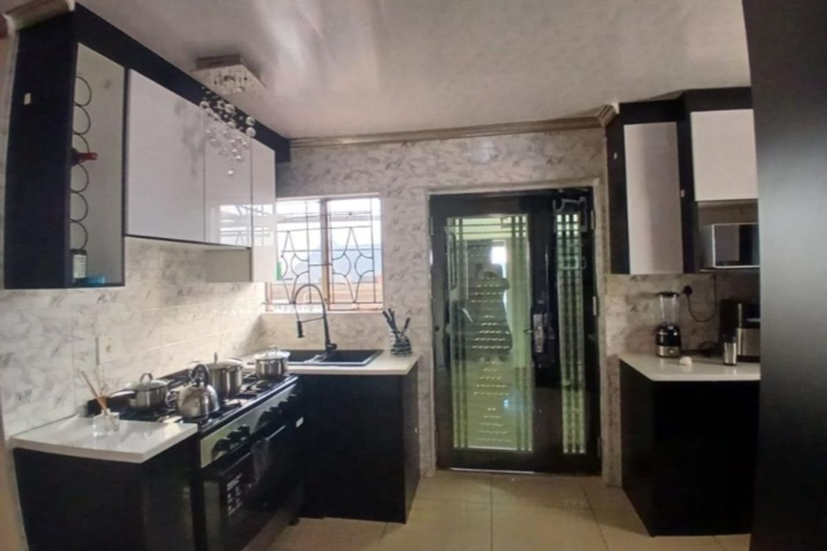 Modern kitchen featuring high-gloss cabinetry, a gas stove with extractor, tiled backsplash, and a secure glass-panelled exterior door.