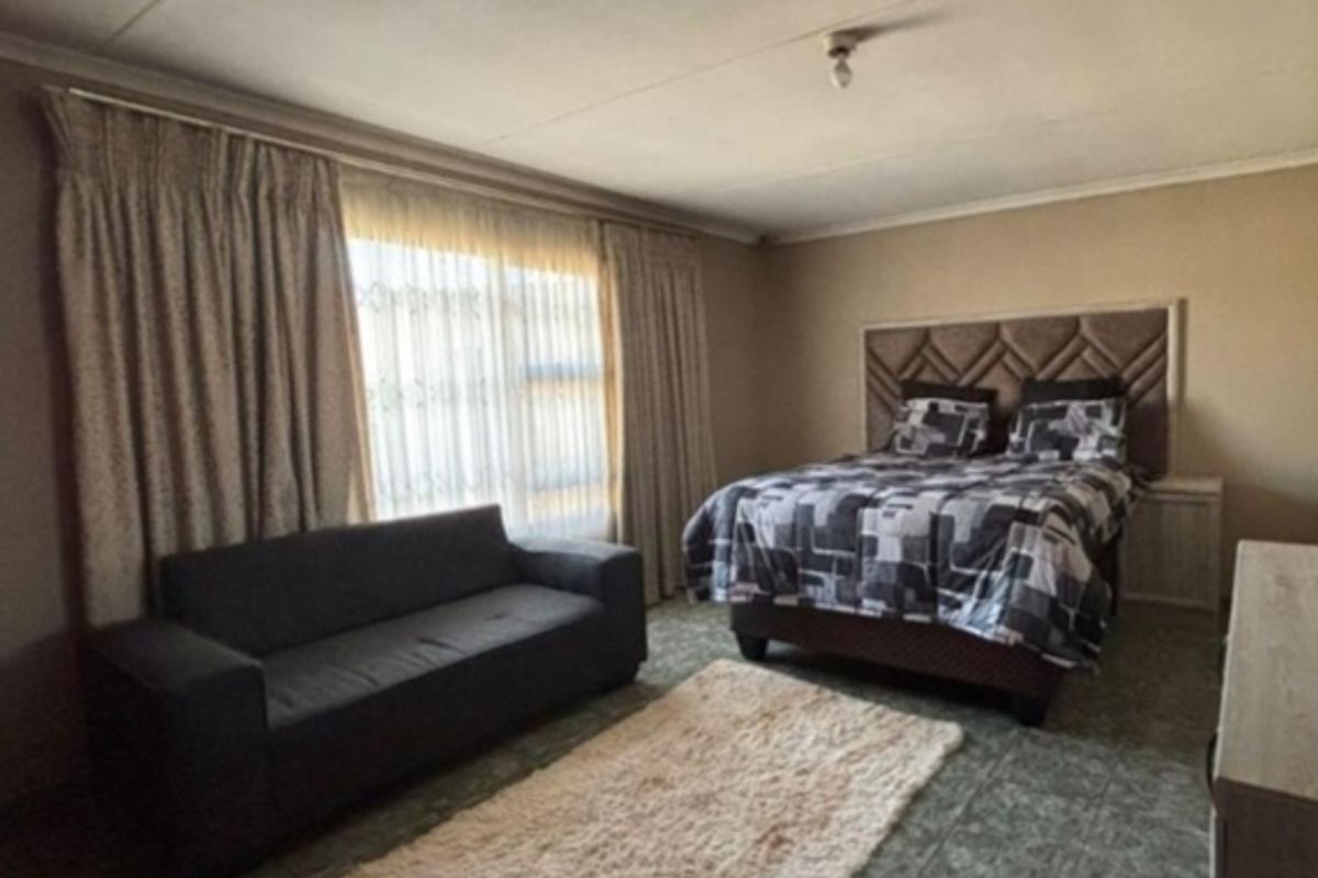 A bedroom featuring tiled flooring and large windows with curtain tracks. The ceiling shows visible signs of wear and cracking.