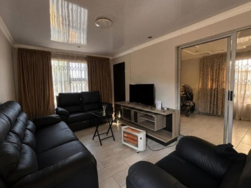 A comfortable living room featuring tiled flooring, recessed ceiling lighting, and a sliding glass door leading to an adjacent space.