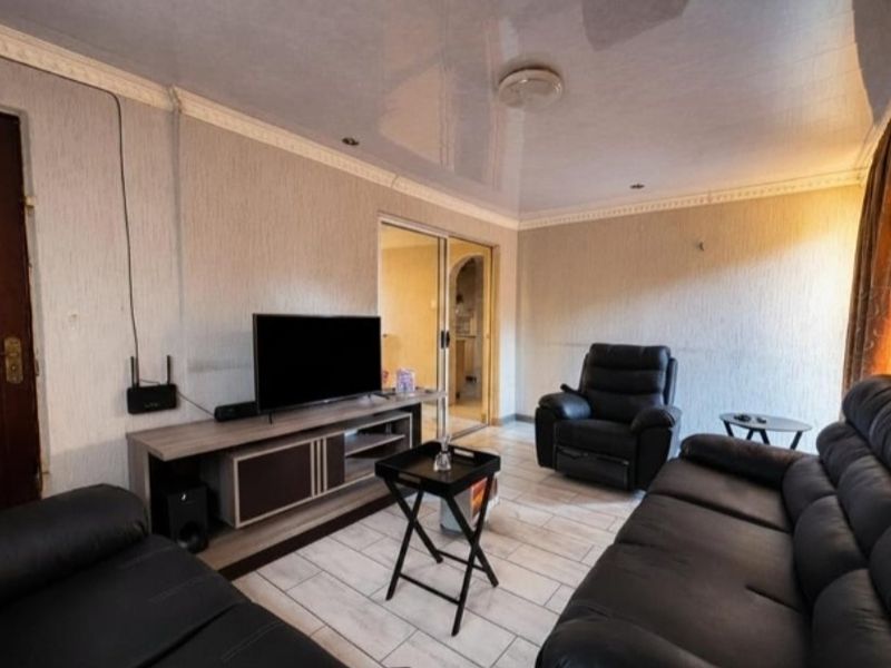 A living room featuring tiled flooring, a glossy ceiling with recessed lighting, and a sliding door leading to an adjacent space.