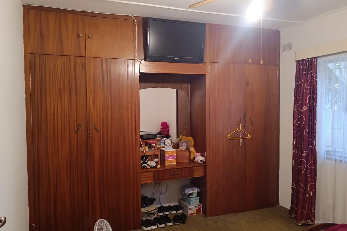 Bedroom featuring extensive floor-to-ceiling built-in wooden cabinetry with an integrated vanity and overhead storage.
