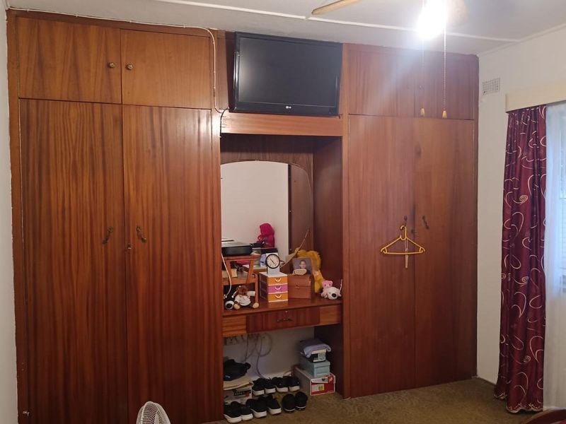 Bedroom featuring extensive floor-to-ceiling built-in wooden cabinetry with an integrated vanity and overhead storage.