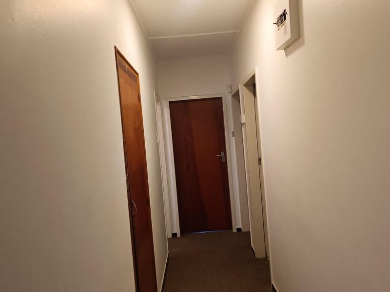 A functional hallway featuring carpeted flooring and multiple internal doors providing access to various rooms within the home.