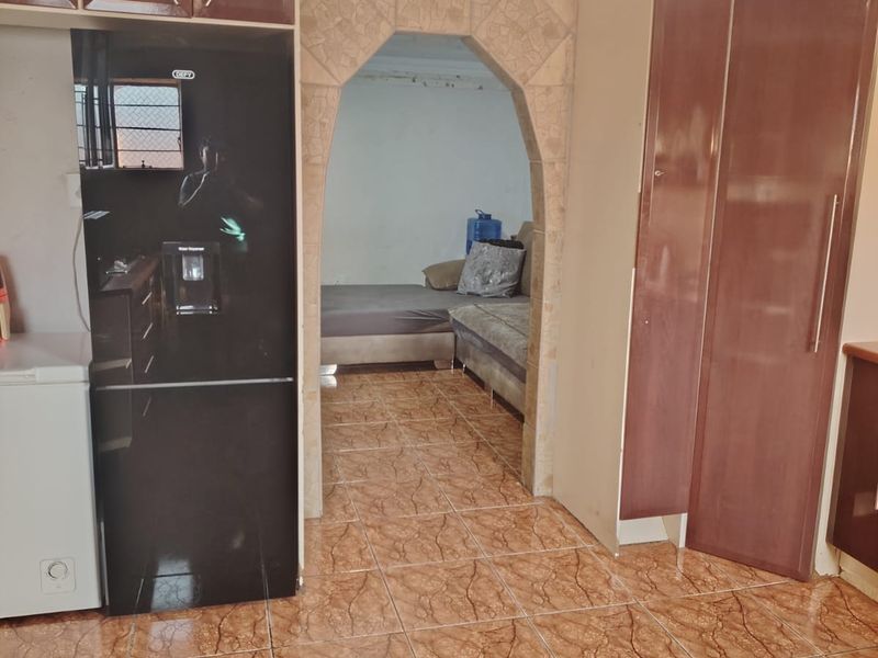 Kitchen area featuring built-in cabinetry, tiled flooring, and a distinctive arched doorway leading to an adjacent living space.