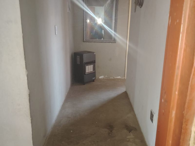 A narrow hallway featuring plain walls, exposed flooring, and an electrical distribution board, requiring cosmetic updates to improve the overall finish.