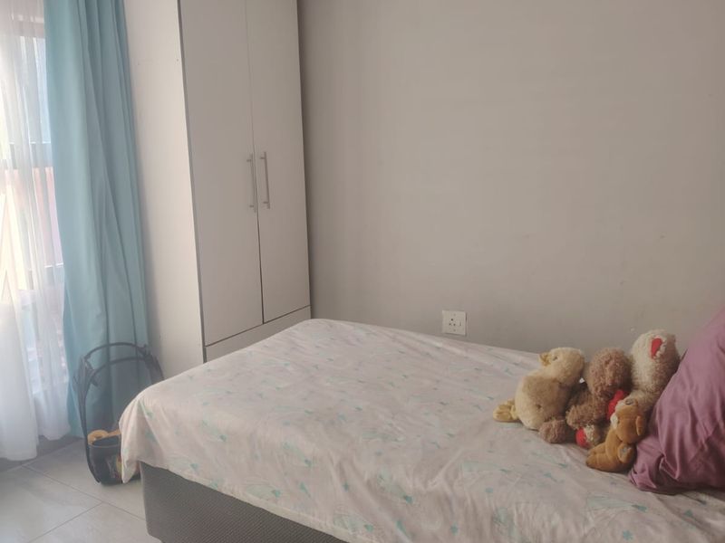 A functional bedroom featuring tiled flooring and a built-in wardrobe, providing essential storage space.