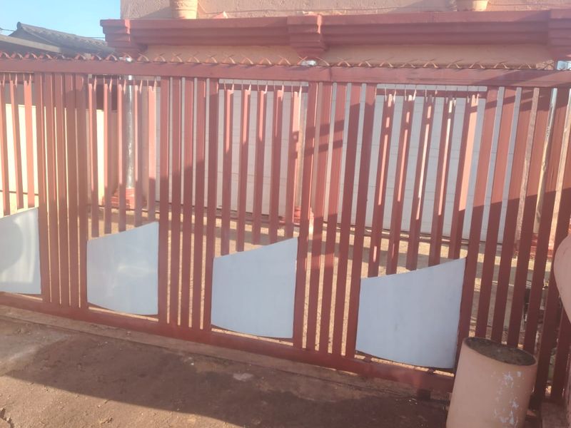 A front view of the property featuring a metal sliding gate and a concrete driveway entrance.
