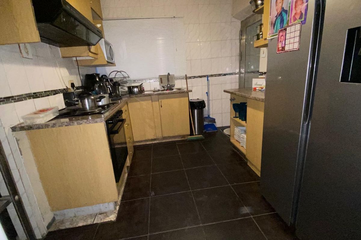 A functional kitchen featuring laminate cabinetry, built-in oven, extractor fan, and tiled surfaces, offering potential for modernization and aesthetic updates.