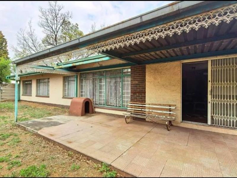 A covered outdoor patio area featuring tiled flooring, decorative metal eaves, and a secure sliding glass door entrance to the home.