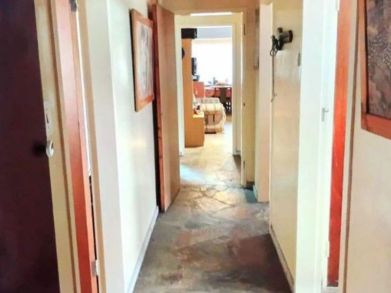 A narrow hallway featuring stone flooring and wooden door frames, providing access to other rooms within the home.