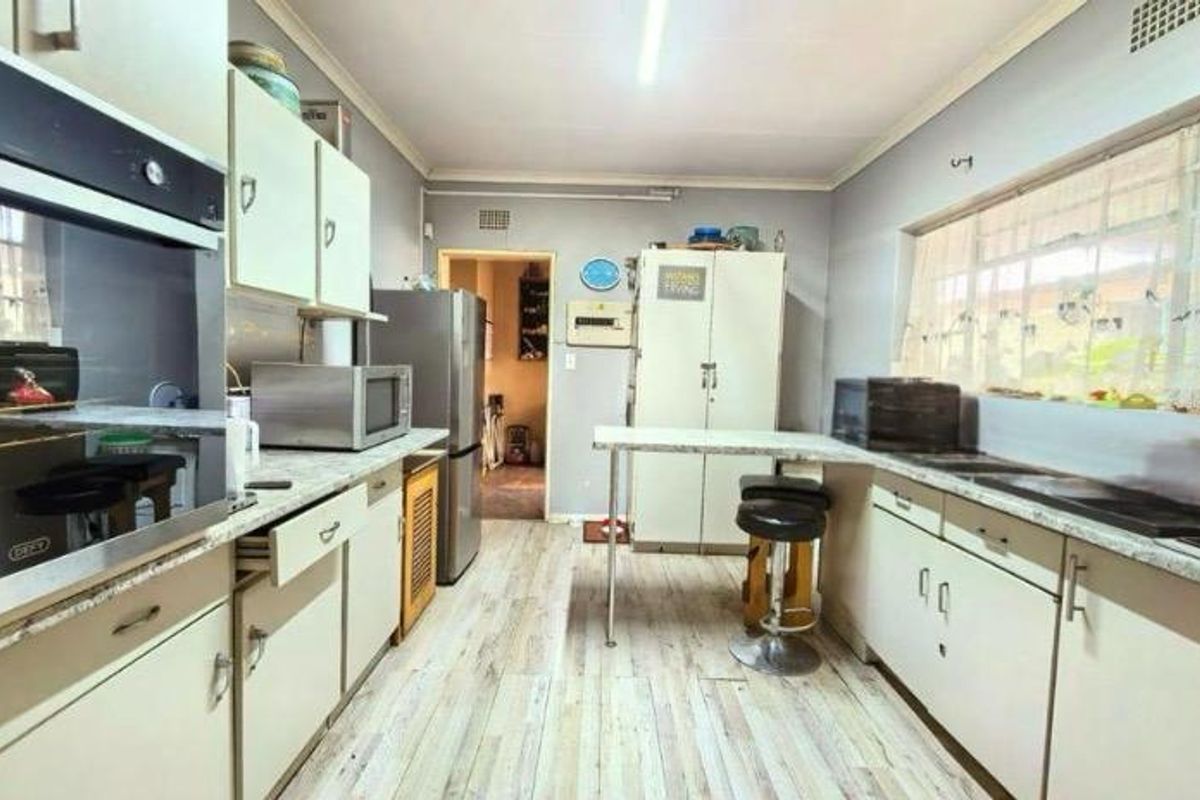 A functional kitchen featuring built-in cabinetry, laminate countertops, a built-in oven, and a double sink with ample natural light.