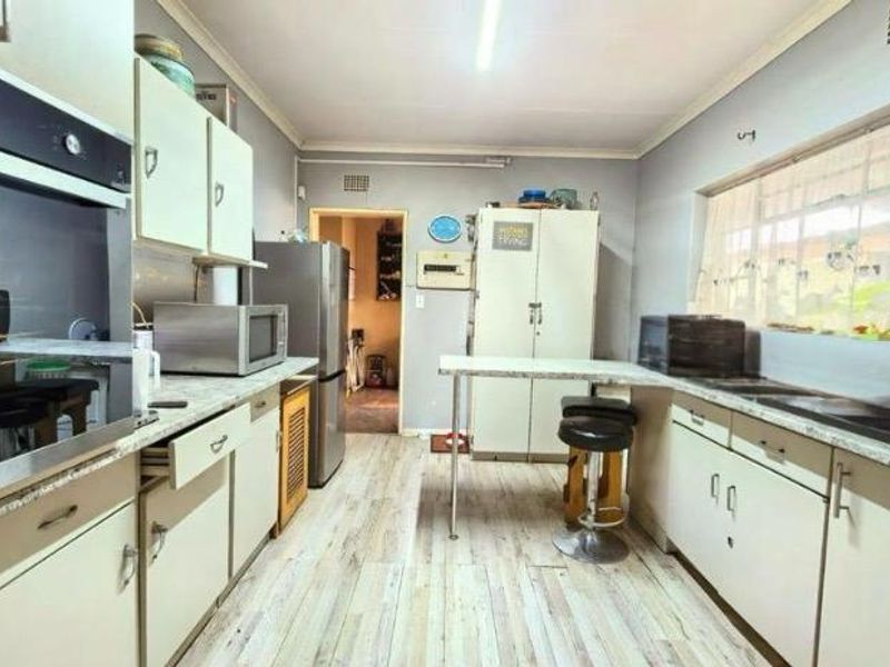 A functional kitchen featuring built-in cabinetry, laminate countertops, a built-in oven, and a double sink with ample natural light.