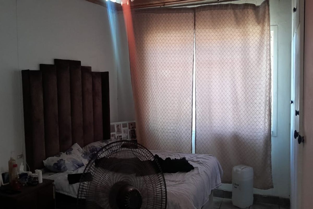 A bedroom featuring a built-in cupboard and natural light through window curtains.