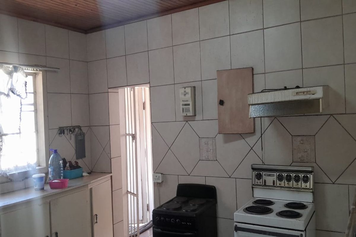 A dated kitchen featuring tiled walls, timber ceiling, and built-in cabinetry, offering significant potential for modernization and renovation.