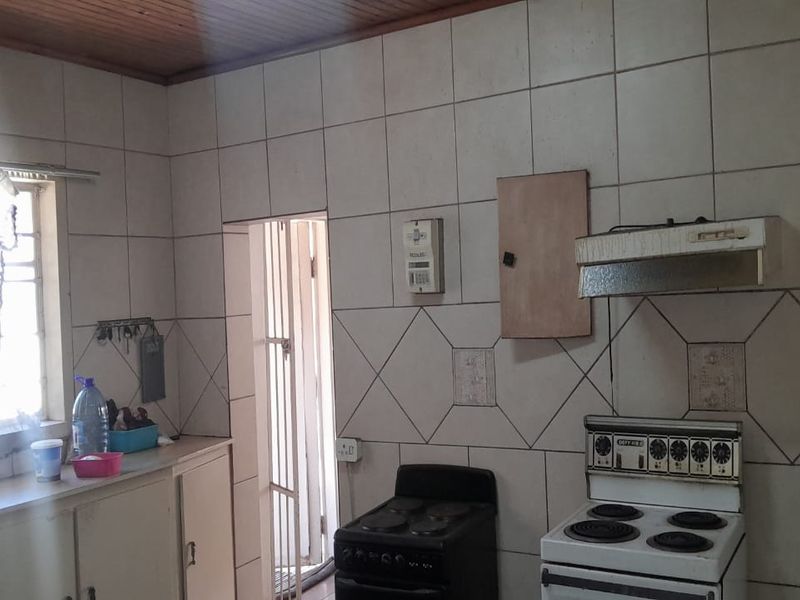 A dated kitchen featuring tiled walls, timber ceiling, and built-in cabinetry, offering significant potential for modernization and renovation.