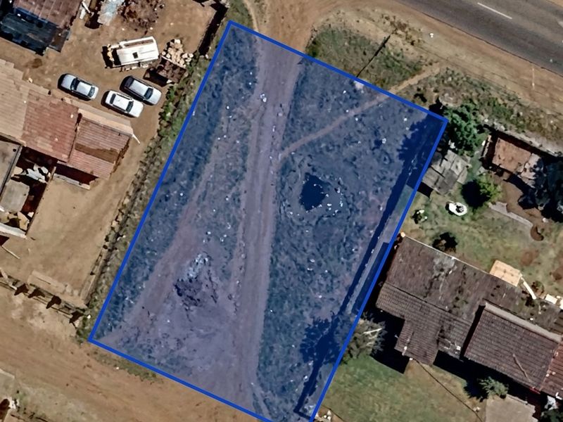 Aerial view of a vacant residential plot with direct road access, situated in a developed neighborhood.