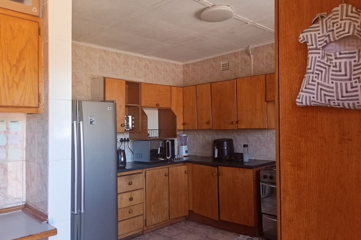 A functional kitchen featuring traditional wooden cabinetry, tiled backsplash, and tiled flooring, offering a classic layout with potential for modern updates.