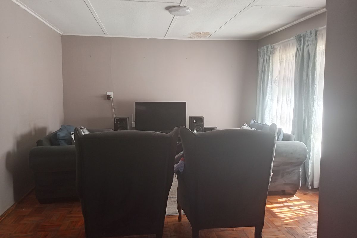 A living room featuring traditional parquet flooring and a ceiling with visible water damage, offering a blank canvas for renovation.