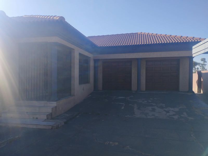 Front elevation of the property featuring a double garage, paved driveway, and tiled roof structure.