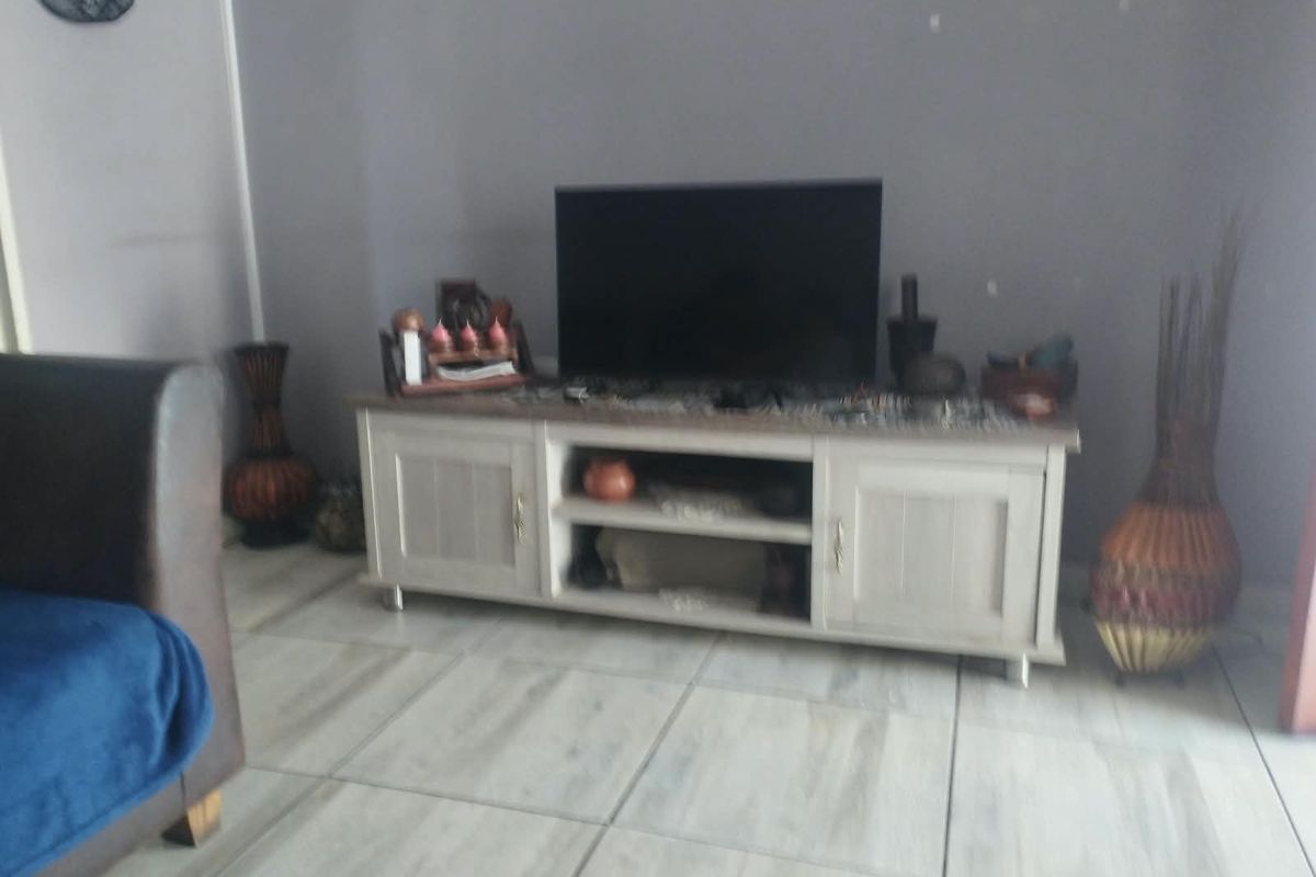 A living room area featuring light-toned tiled flooring and neutral wall finishes, providing a functional space for entertainment.
