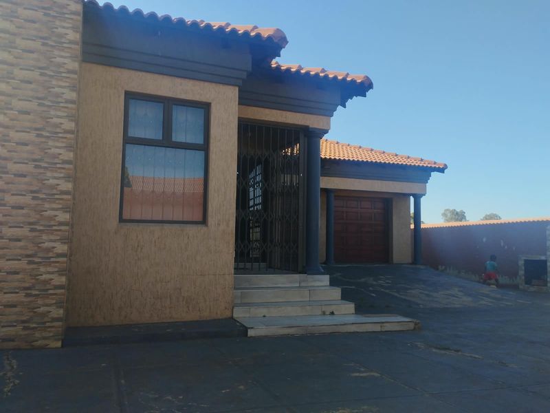 Front elevation of a residential property featuring a tiled roof, stone cladding accents, a paved driveway, and an integrated garage.