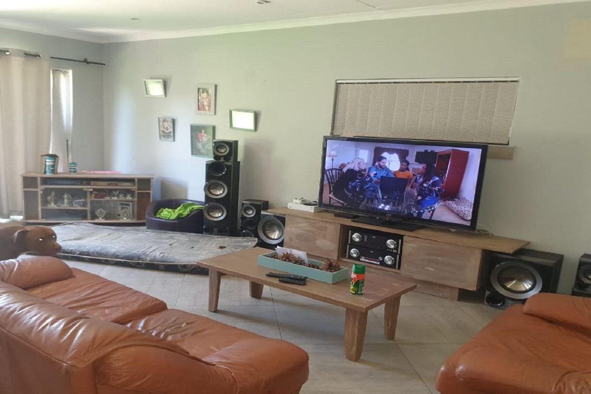 A spacious living room featuring tiled flooring, recessed ceiling lighting, and large windows with curtains, providing a comfortable area for relaxation.