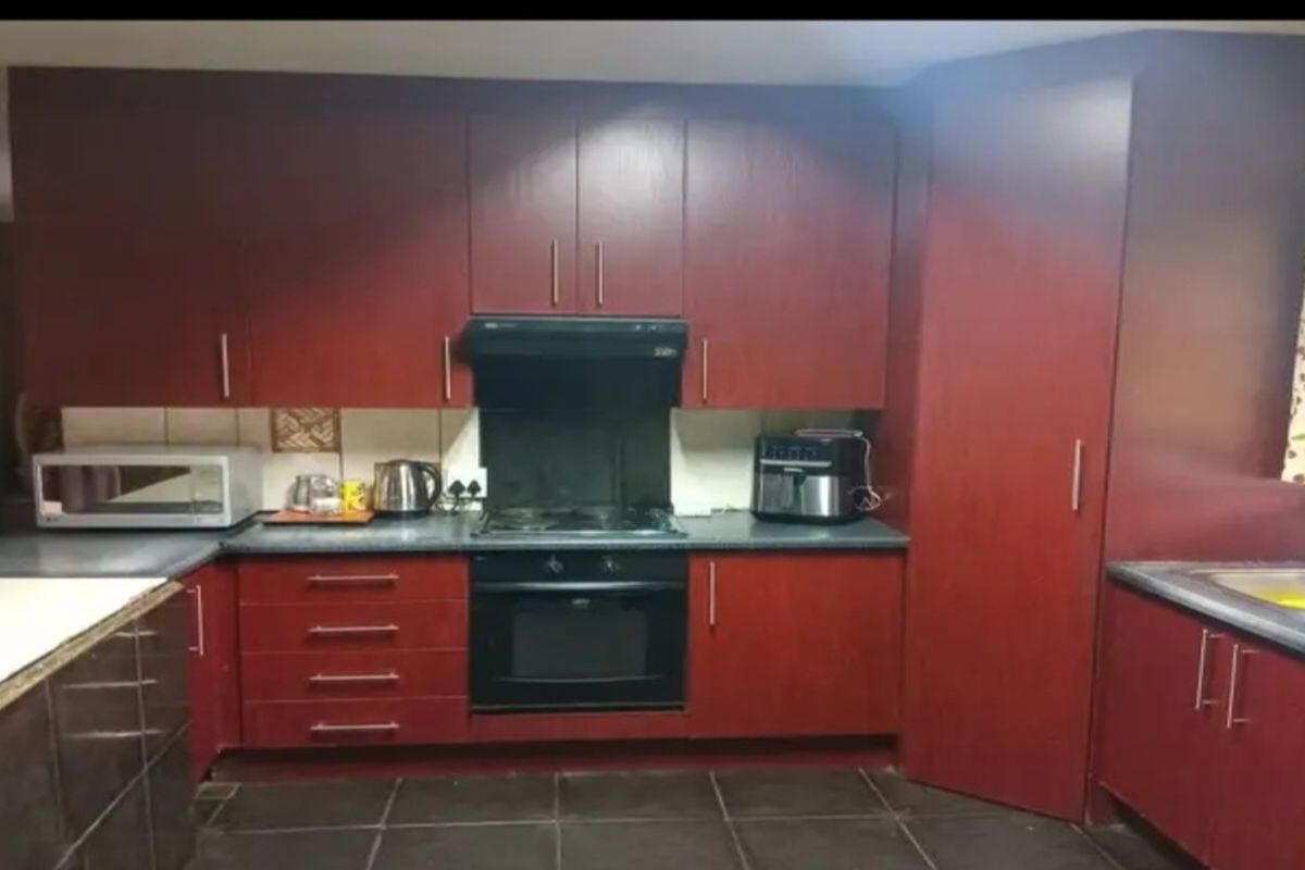A functional kitchen featuring dark wood cabinetry, a built-in oven, extractor fan, and tiled flooring.