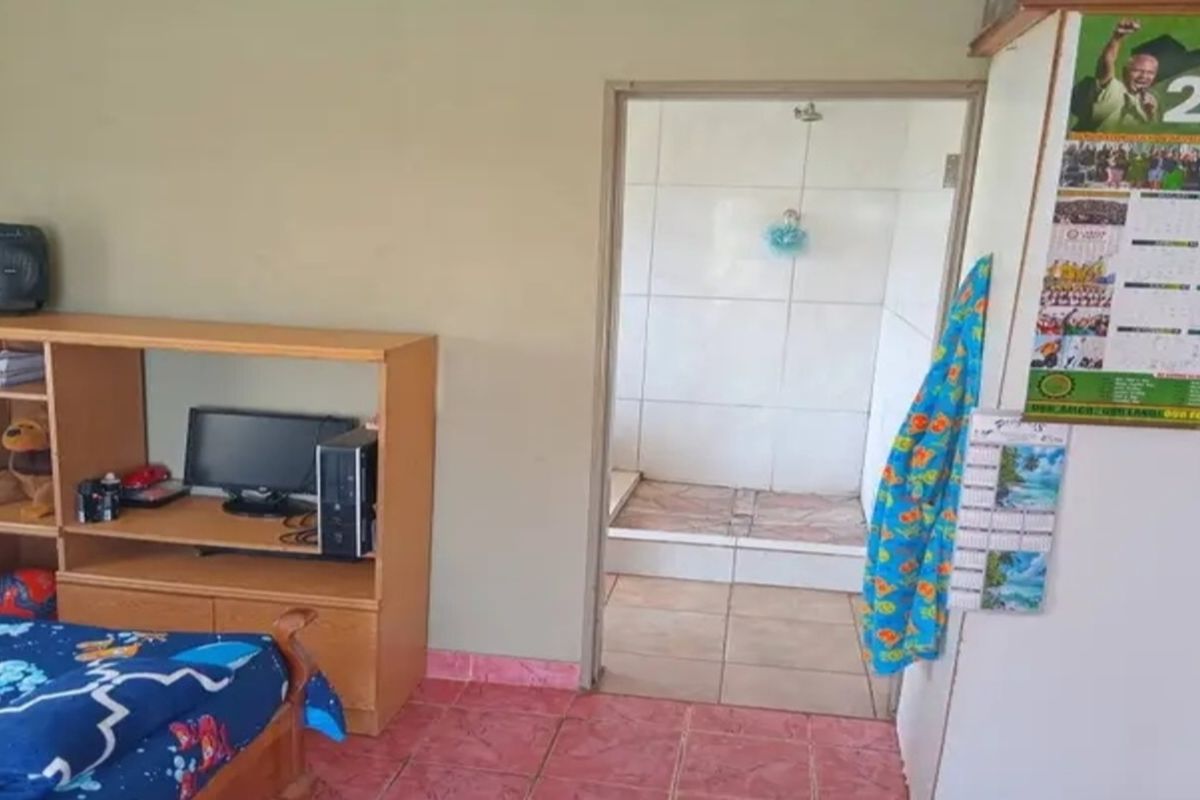 A bedroom featuring tiled flooring with an adjoining en-suite bathroom area, providing functional living space within the farm property.