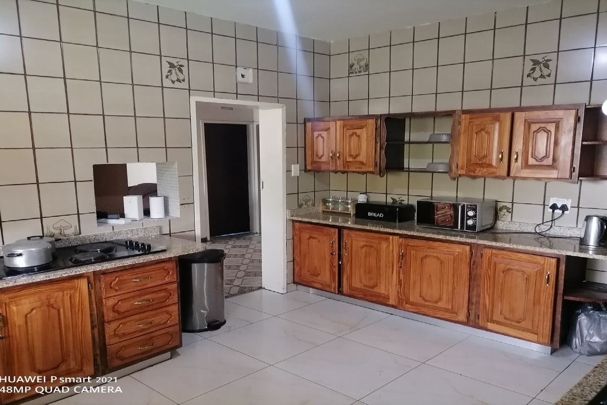 A functional kitchen featuring wooden cabinetry, granite-style countertops, and tiled walls, providing ample storage and workspace.