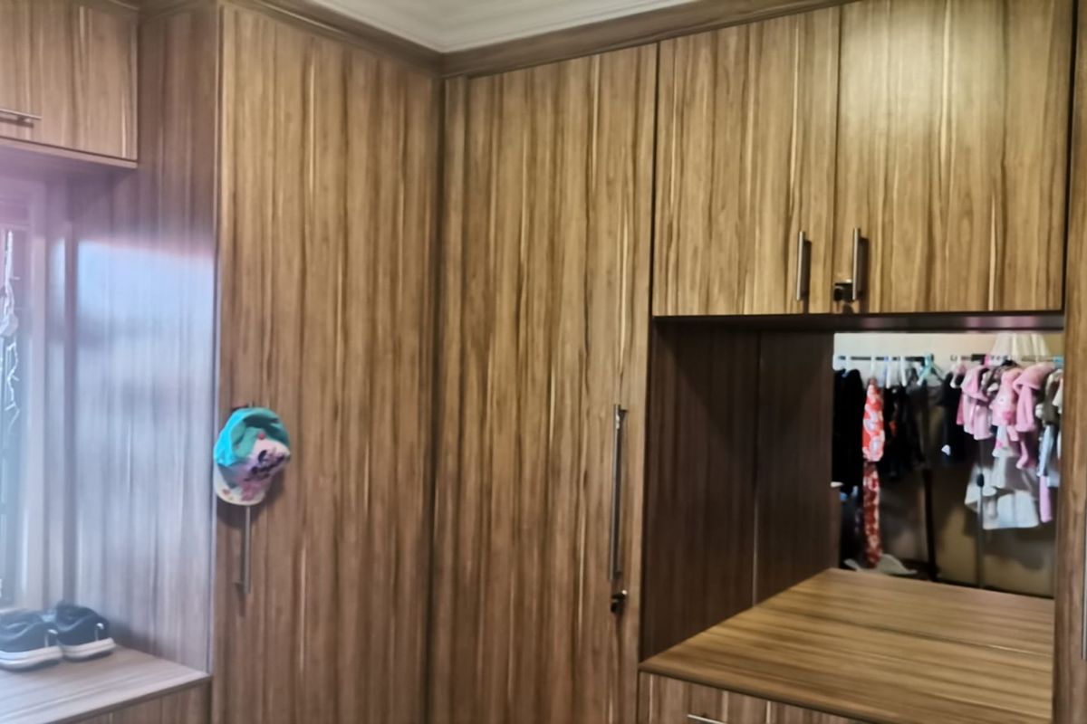 A bedroom featuring extensive built-in wooden cabinetry with integrated shelving and storage space.