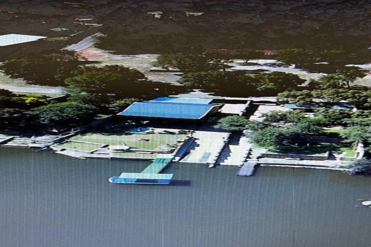 Aerial view of a waterfront property featuring a private jetty, boat ramp, and landscaped garden area along the riverbank.