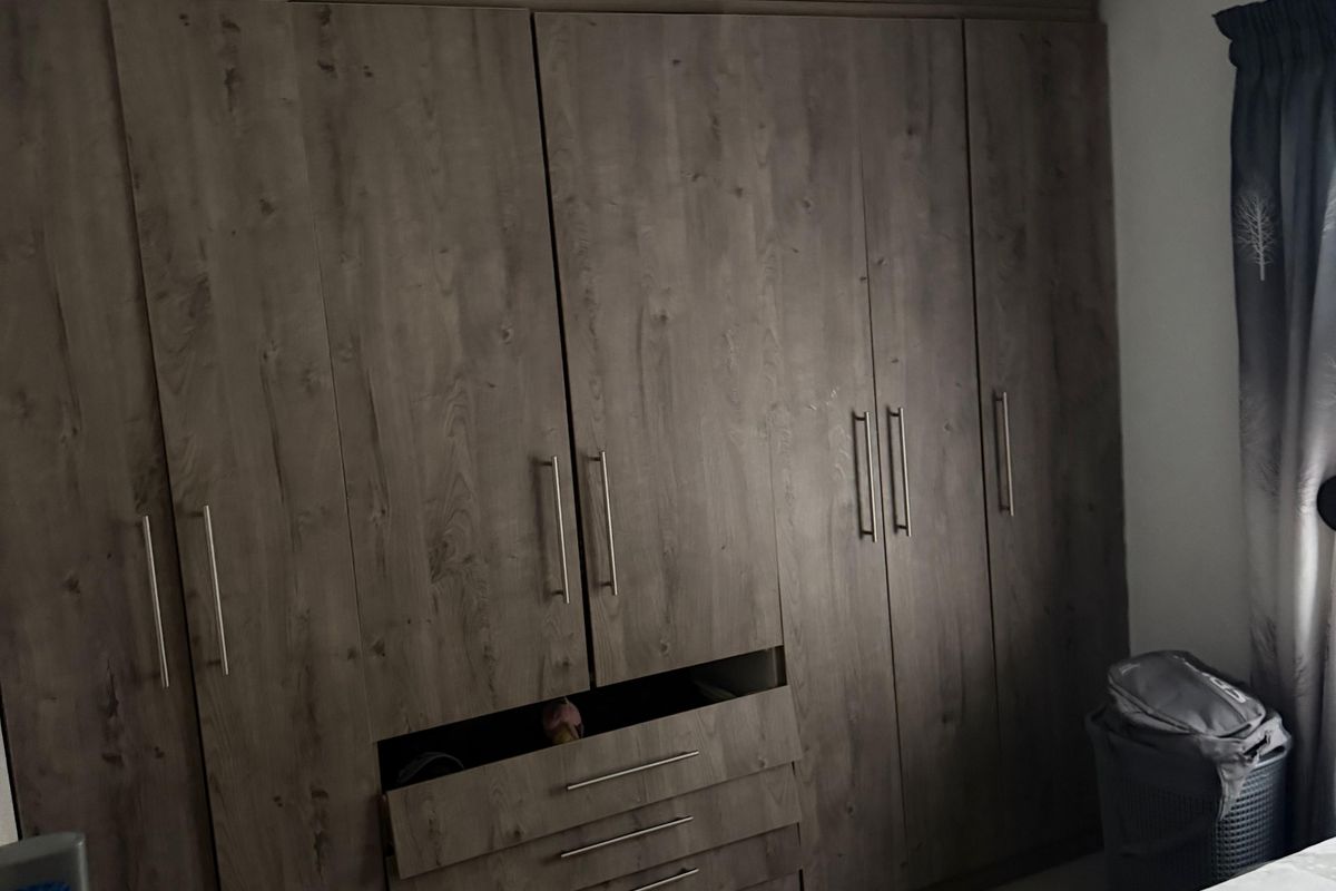 Bedroom featuring built-in floor-to-ceiling wooden cabinetry with integrated drawers and hanging storage space.