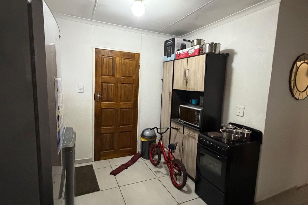 A functional kitchen area featuring tiled flooring, built-in cabinetry, and a freestanding stove, providing a practical space for meal preparation.