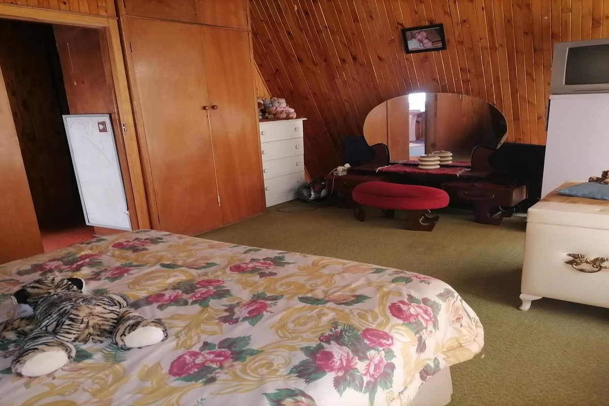 A bedroom featuring a sloped ceiling with wood paneling, built-in wooden cupboards, and carpeted flooring.