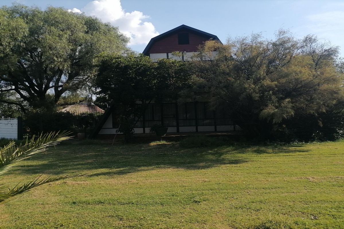 A view of the rear exterior of the property, featuring a multi-level structure set within a spacious, established garden area.