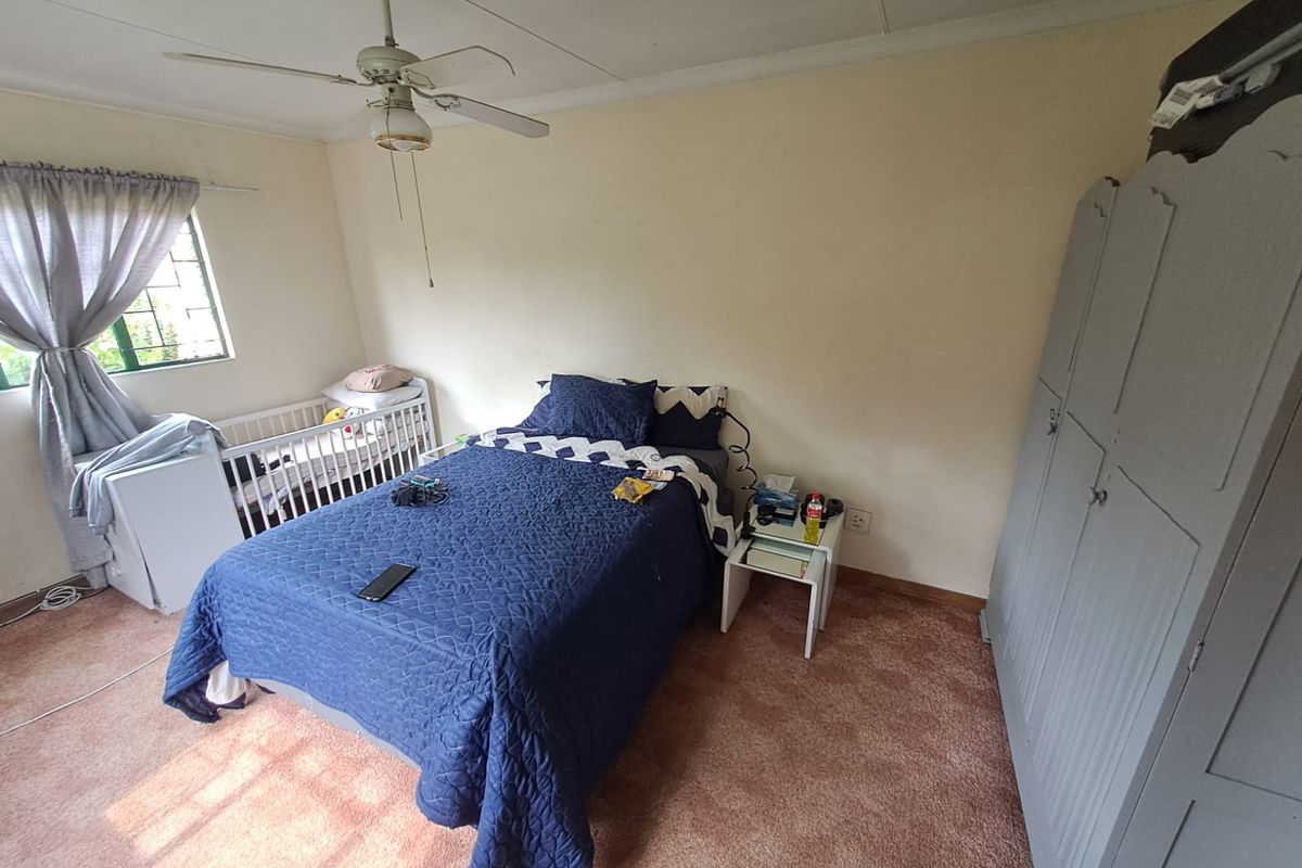 A bedroom featuring carpet flooring, a ceiling fan, and built-in wardrobe storage, offering a functional space with potential for cosmetic updates.