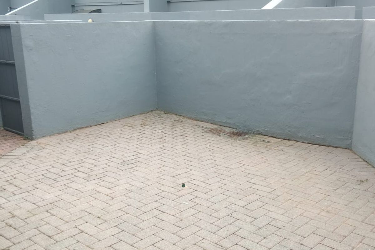 A private paved courtyard area featuring high boundary walls and a secure access gate, providing a functional outdoor space.